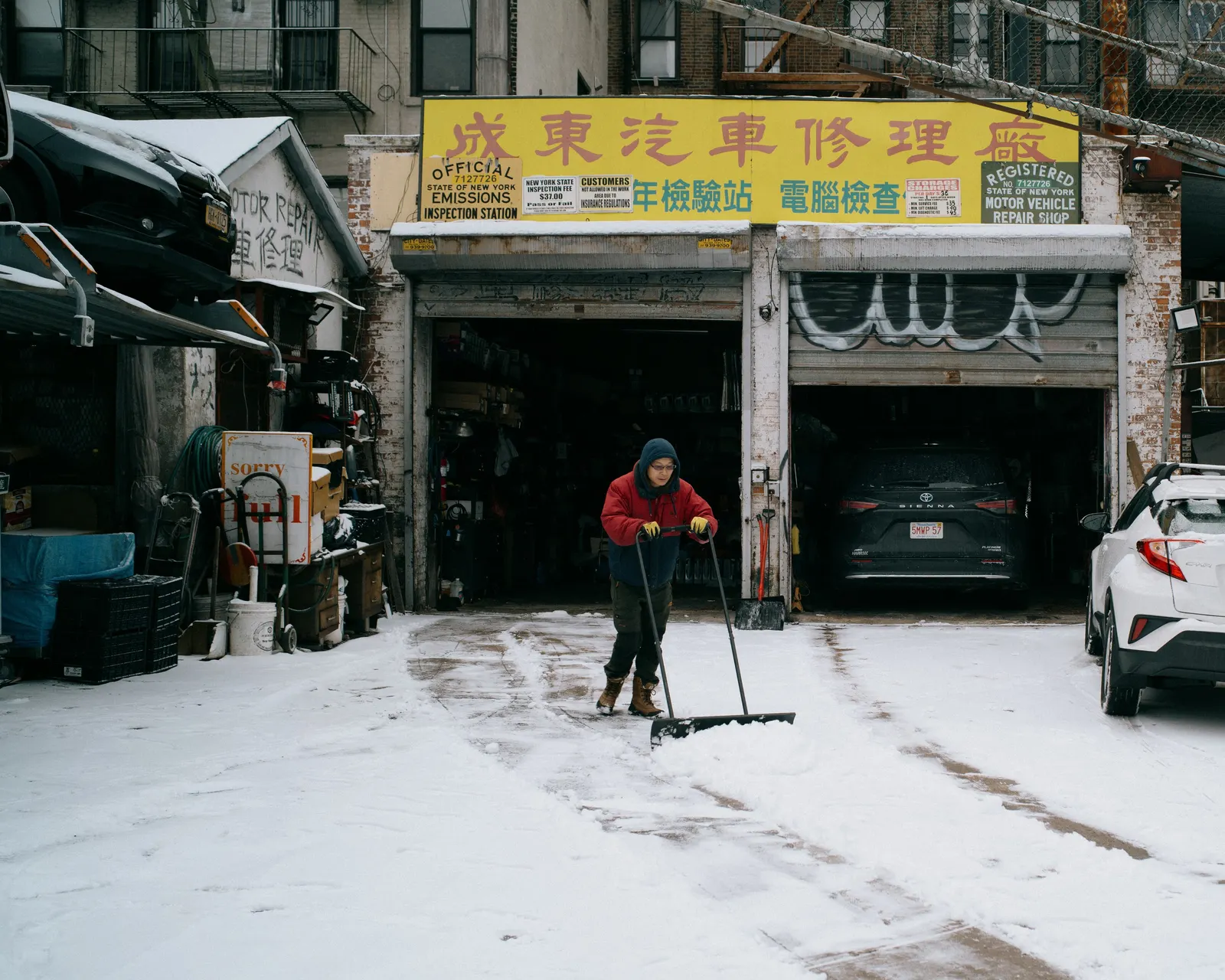 A snowed-in street, shopfronts still lit.